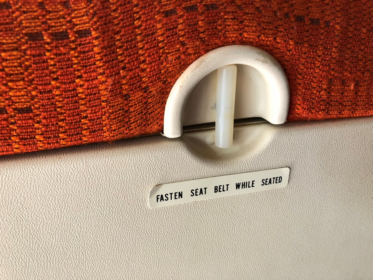 Delta Red Orange Tripple Coach Seats Orange Material Tray Table Latch Close Up
